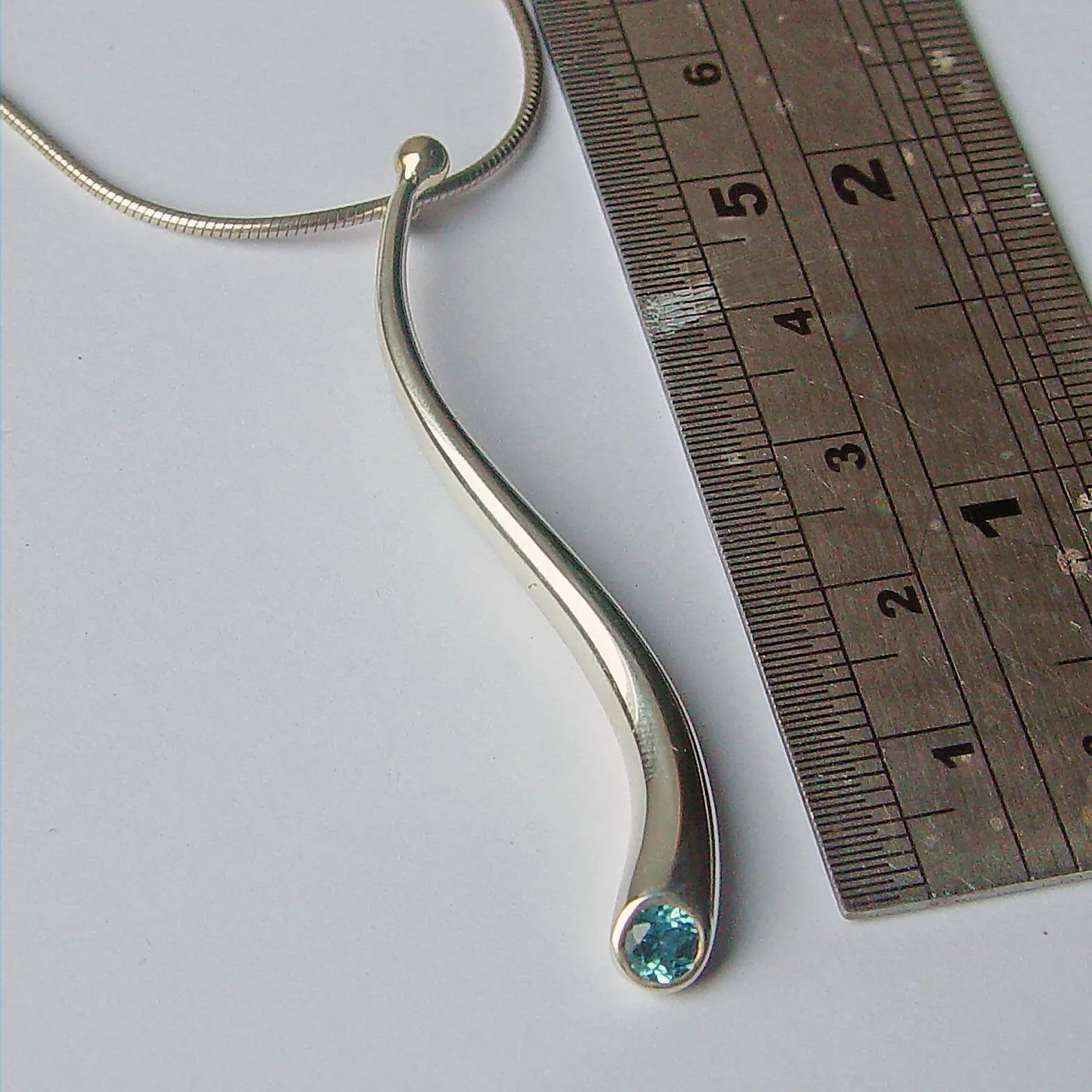 Curving silver wiggly pendant with blue topaz & 18K gold detail